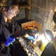 Rochelle hitting my sludgy-encrusted valve cover with some foaming cleaner and a wire brush on a drill.